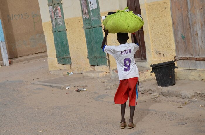Senegalesischer Junge mit Last