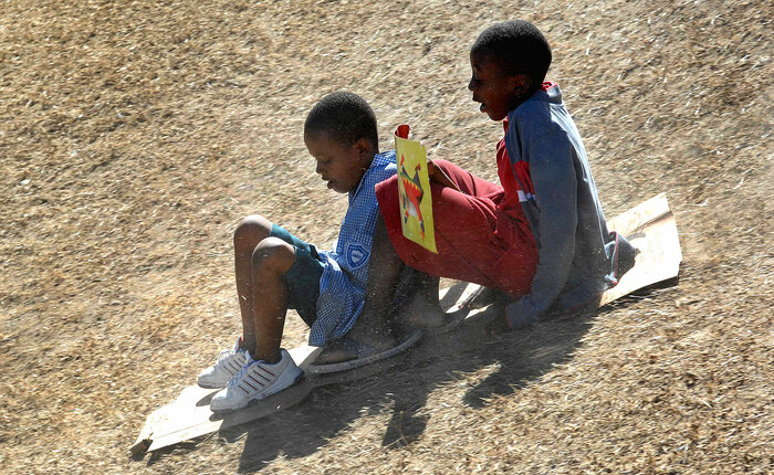Zwei Jungen rutschen einen Hügel hinab, Haiti