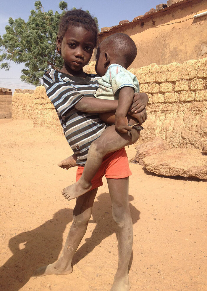 Mädchen aus Burkina Faso trägt ein Kind