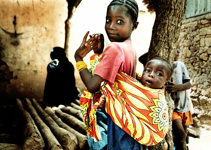 Mädchen in Mali mit Geschwisterchen auf dem Rücken