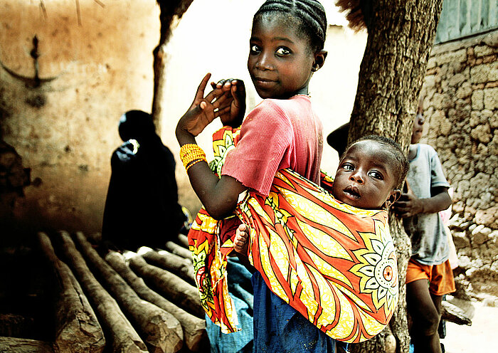 Mädchen in Mali mit Geschwisterchen auf dem Rücken