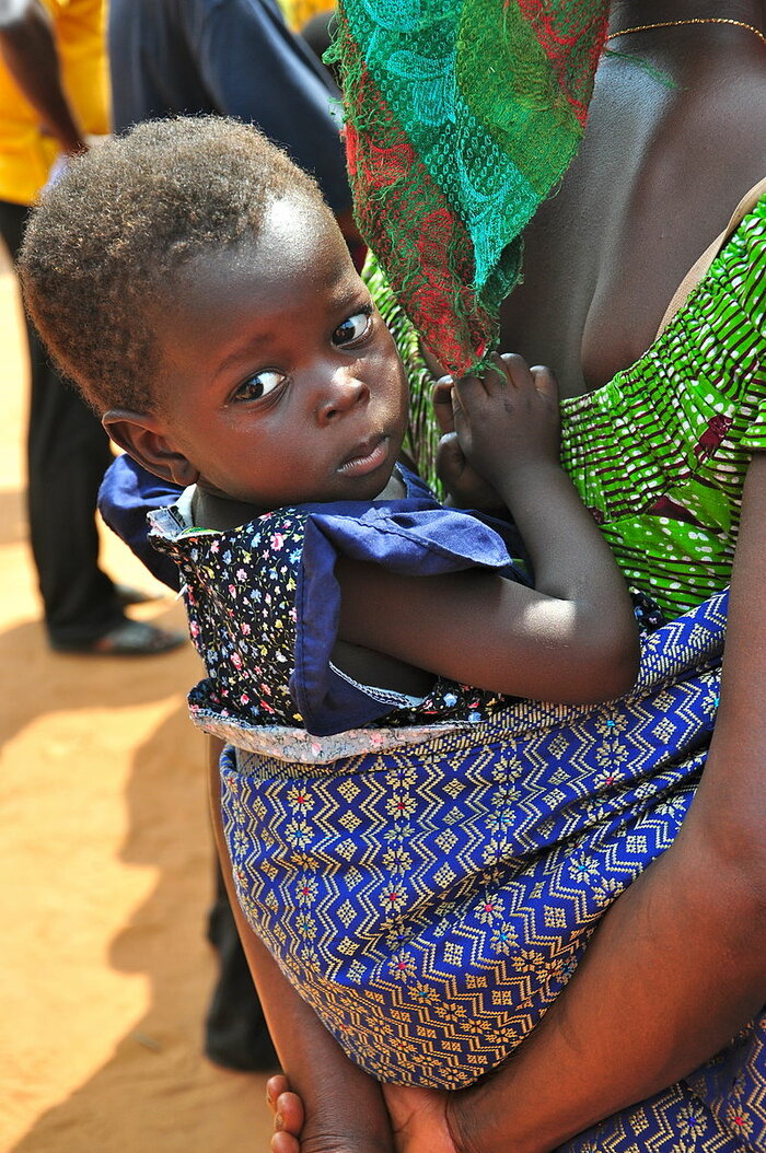 Kleines Mädchen auf dem Rücken der Mutter (Ghana)