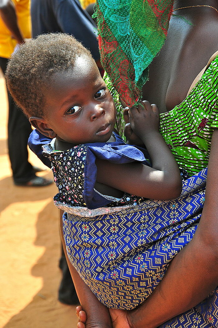 Kleines Mädchen auf dem Rücken der Mutter (Ghana)