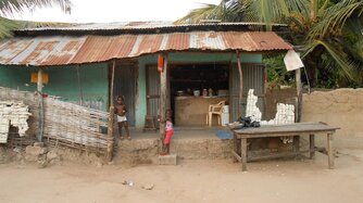 Mädchen in Guinea-Bissau vor einem Dorfladen