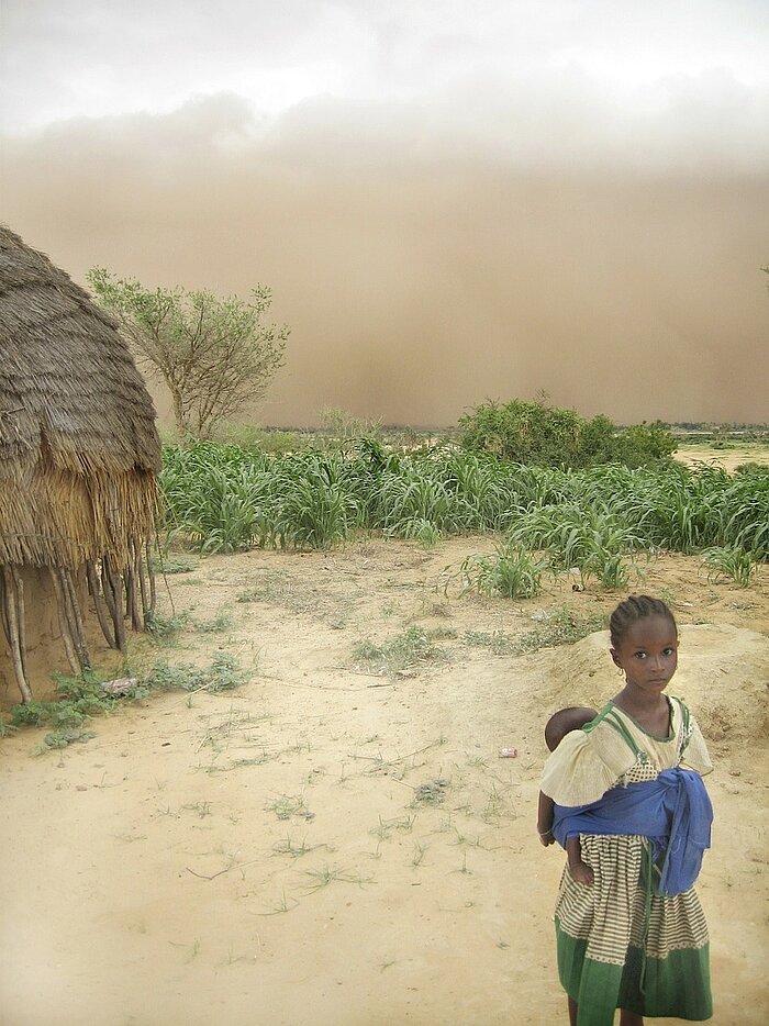 Mädchen trägt Baby auf dem Rücken in NIger