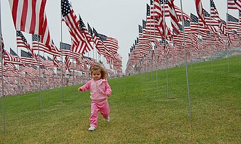 Mädchen läuft durch viele amerikanische Fahnen