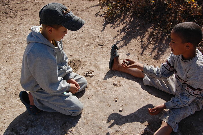Kinder spielen mit Steinen in Marokko
